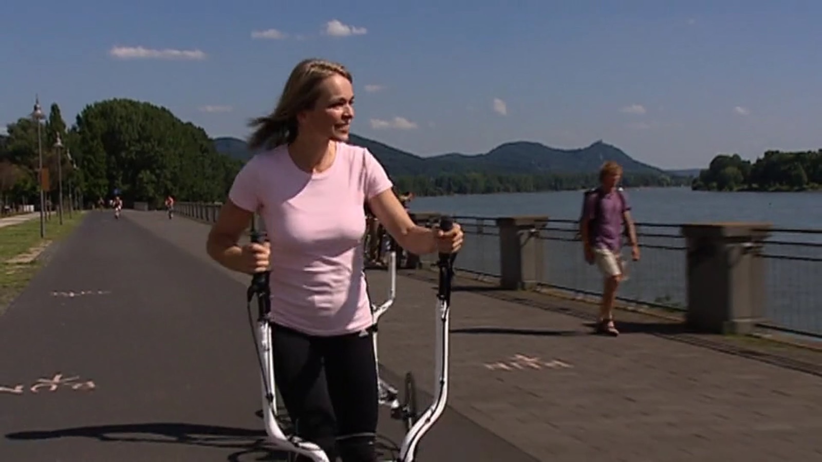 Fahrerin auf dem FreeCross auf einer Uferpromenade — Standbild aus dem Produktvideo